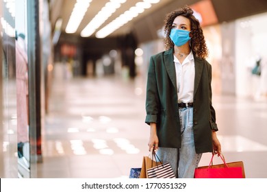 Young woman wearing protection face mask against coronavirus after shopping  in the mall. Purchases, shopping, lifestyle concept. Covid-2019.