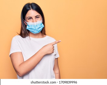 Young woman wearing protection mask for coronavirus disease over yellow background smiling cheerful pointing with hand and finger up to the side - Powered by Shutterstock