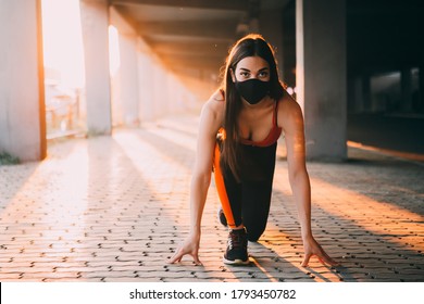 Young woman wearing protective face mask and getting ready to run