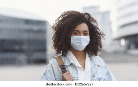 Young woman wearing protective face mask in a city. Masked african-american teenage student girl on a city street. Epidemic, pandemic, corona virus protection, healthy lifestyle, people concept - Powered by Shutterstock