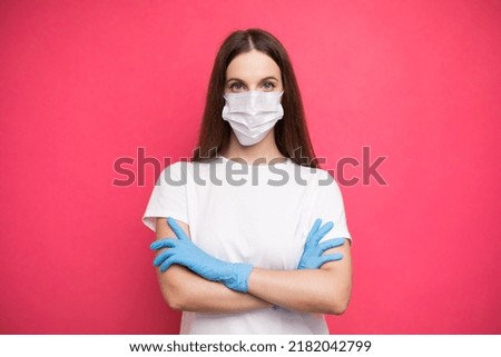 Young woman wearing protective mask on face and medical gloves keeping arms crossed. Confident girl, female doctor in medical mask and protective gloves.