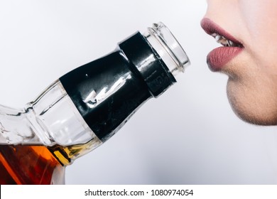 Young Woman Wearing A Sexy Black Suit, Holding A Bottle Of Whiskey.Young Beautiful Woman In Depression, Drinking Alcohol