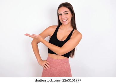 young woman wearing sportswear over white studio background says: wow how exciting it is, has amazed expression, shows something on blank space with palm. Advertisement concept. - Shutterstock ID 2263101997