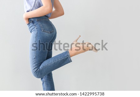 Young woman wearing stylish jeans pants on light background