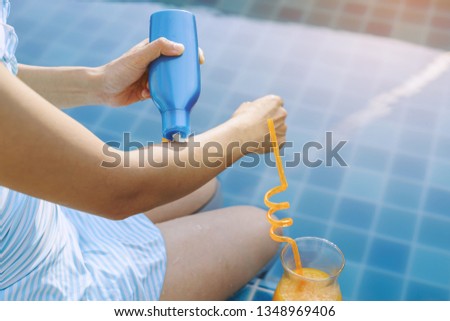 Young woman wearing swimsuit applying sunscreen lotion at swimming pool, Summer vacation concept