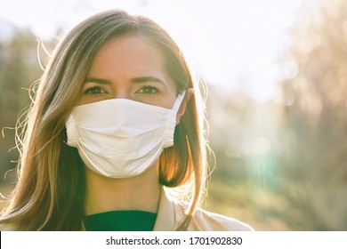 Young Woman Wearing White Cotton Virus Mouth Nose Mask, Nice Backlight Sun Bokeh In Background, Closeup Face Portrait