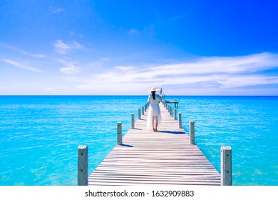 Young woman wearing white dress and hat standing on a wooden pier  enjoying the sea.Happy summer vacation - Powered by Shutterstock