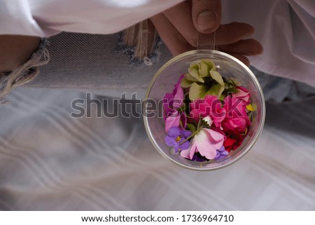 Young woman wearing white shirt and jeans holding cup of spring flowers. Cozy time at home. top view.