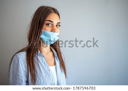 Young woman wears protective face mask, wrong way, incorrect wearing - masks should cover nose as well. How to NOT wear a mask. The wrong way to wear a mask on the chin and open nose