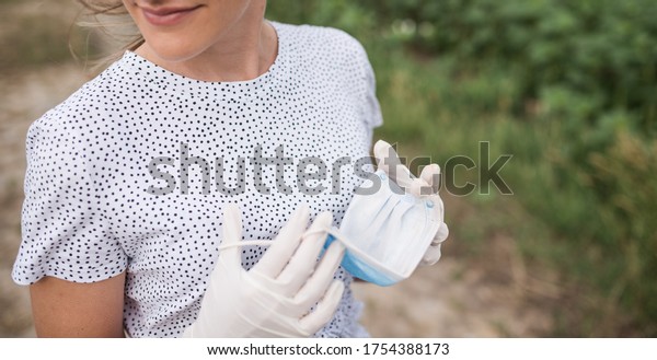 young woman wears a virus protection\
mask and wears surgical sterile gloves on her\
hands
