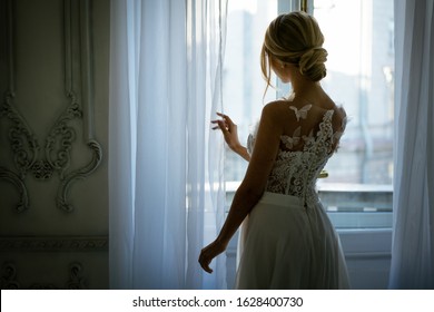 A Young Woman In A Wedding Dress And Hairstyle Is Standing At The Window, A Beautiful Silhouette