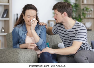 young woman weeping being conforted by husband
