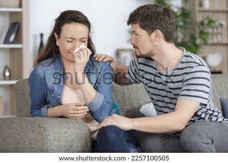 young woman weeping being conforted by husband