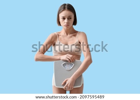 Young woman with weight scales on color background. Anorexia concept Imagine de stoc © 
