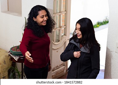 A Young Woman Welcoming Another Woman Into Her Home In Winter