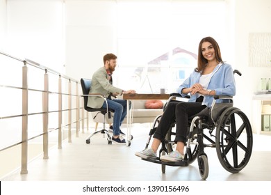 Young Woman In Wheelchair With Colleague At Office