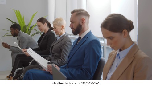 Young Woman In Wheelchair Waiting In Line For Job Interview In Office Corridor. Disabled Female Job Applicant In Office Corridor Waiting In Row For Business Meeting With Employer