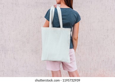 Young woman with white cotton bag in her hands.