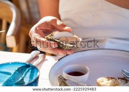 Young woman in white dress eats fresh live creuze oysters with marinated onion, seafood in French restaurant ストックフォト © 