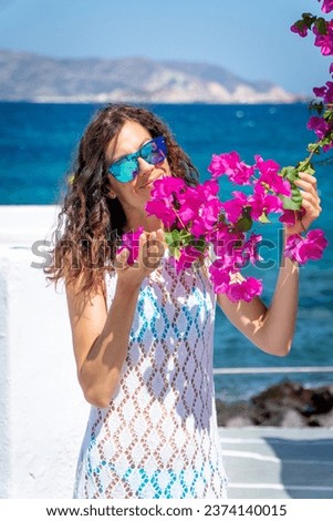 Young woman in white dress playing with a bougainvillea