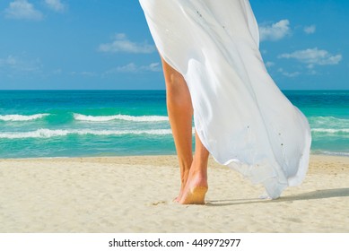 Young Woman In White Dress Walking Alone On The Beach