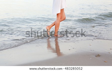 Young woman in white dress walking alone on the beach