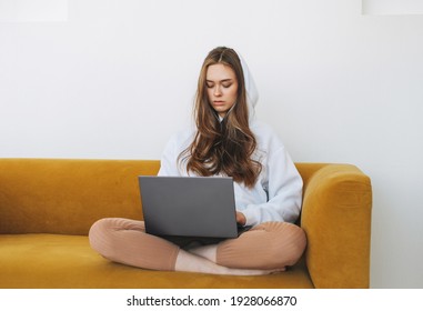 Young Woman In White Hoodie Beautiful Girl Freelancer Student Using Laptop Sitting On Yellow Couch In The Modern Interior