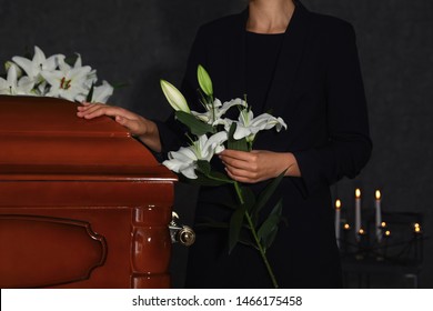 Young Woman With White Lilies Near Casket In Funeral Home, Closeup