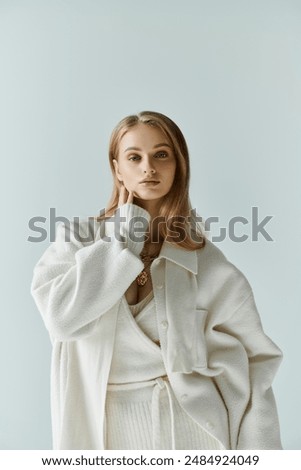 A young woman in a white outfit poses against a blue backdrop.
