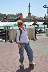 Young Woman In White Shirt And Jeans Stands In The Port Of Deira On The Dock Of Dubai.UAE