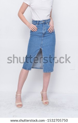 Young woman in white shirts with fashionable denim jeans skirt and high hell shoes posing
