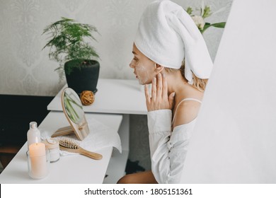 Young woman in white towel chilling in bedroom and making clay facial mask near mirror. Girl doing beauty treatment and relaxing at home. Morning skin care beauty routine, self care. - Shutterstock ID 1805151361