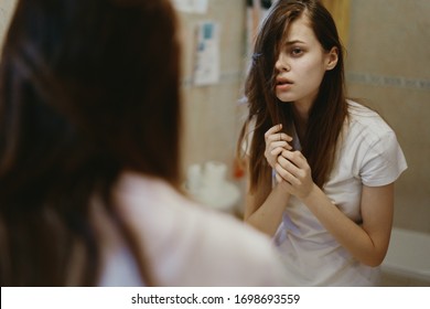 young woman in white t-shirt in the bathroom with her hair - Shutterstock ID 1698693559