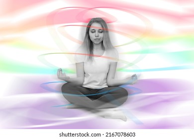 A young woman in a white t-shirt sitting in the lotus position meditates holding fingers in yoga sign with rays of abstract circulating colored energies around. Spirituality, awakening, enlightenment