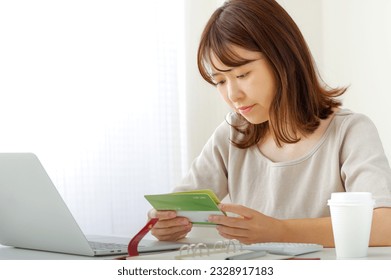A young woman who calculates money.
						
						The passbook held by a woman is listed as "savings account" in Japanese.