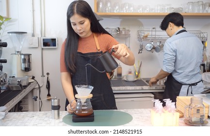 Young Woman Who Is Coffee Shop Business Owner Pours Hot Water To Make Drift Coffee Within Modern Cafe.