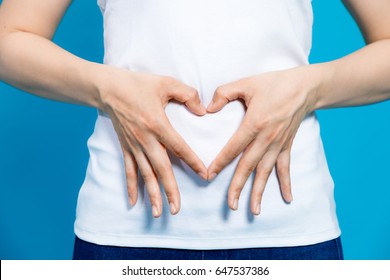 young woman who makes a heart shape by hands on her stomach. - Shutterstock ID 647537386