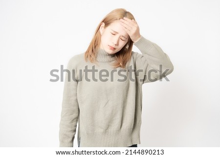 A young woman who is sick and puts her hand on her head