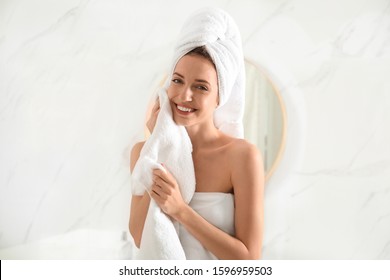 Young Woman Wiping Face With Towel In Bathroom