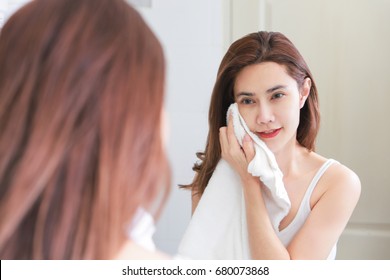 Young Woman Wiping Her Face With Towel In Bathroom.