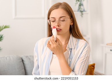 Young Woman Wiping Nosebleed With Tissue At Home, Closeup