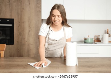 Young woman wiping table with paper towel in kitchen - Powered by Shutterstock