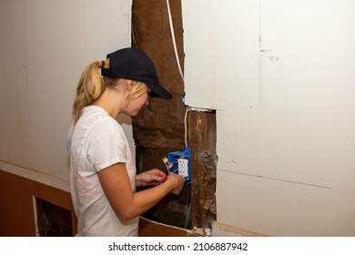 A young woman wiring a new electrical outlet as part of a DIY home improvement project.