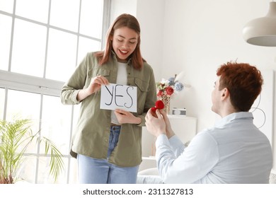 Young woman with word YES get proposed by her boyfriend at home - Shutterstock ID 2311327813