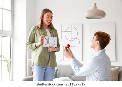 Young woman with word YES get proposed by her boyfriend at home - Shutterstock ID 2311327819