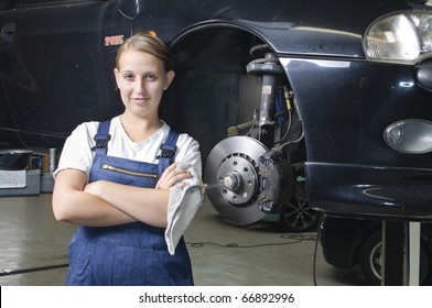 Young woman in work clothes, Apprentice is next to a car and is proud and happy in a garage - Powered by Shutterstock