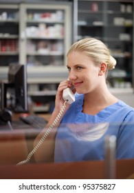 Young Woman At Work As Receptionist And Nurse In Hospital And Talking On The Phone