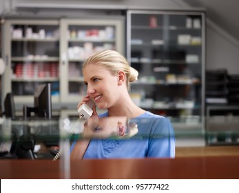 Young Woman At Work As Receptionist And Nurse In Hospital And Talking On The Phone