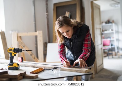 Young Woman Worker In The Carpenter Workroom.