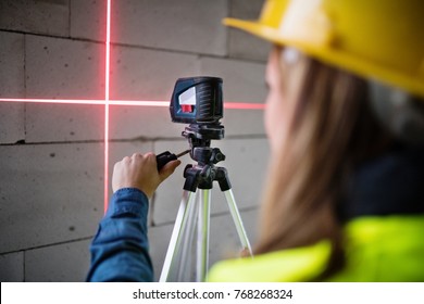 Young Woman Worker With Laser On The Building Site.